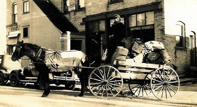 Mailman delivering mail on horse and buggy.